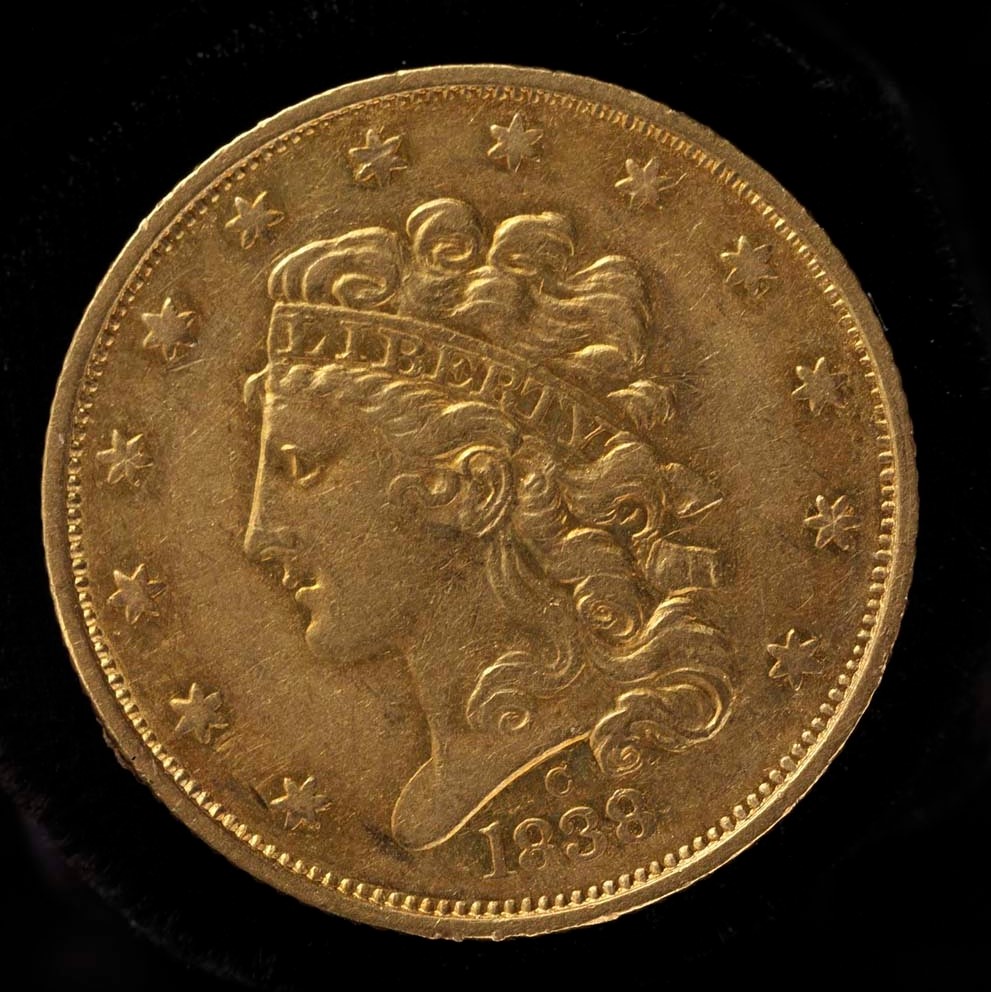 Gold coin marked 1838 decorated with stars and the profile of Liberty's head. Liberty wears a head-band that reads "Liberty."