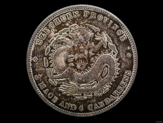 A Chinese coin with a coiled dragon on it. Around the edges there is writing in English.