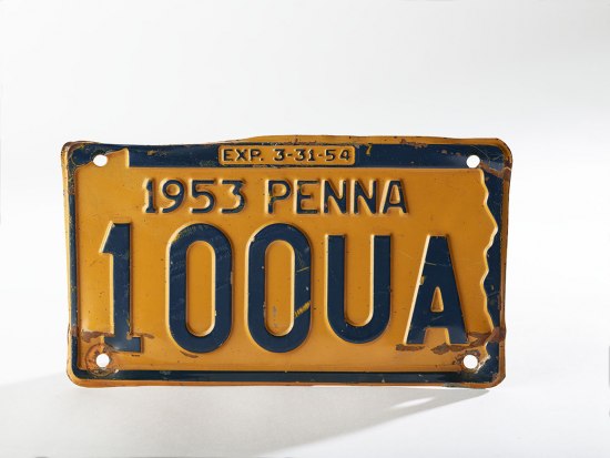 A Pennsylvania license plate. It is yellow with blue outline and numbers/letters