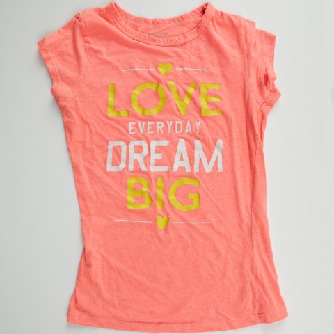 A pink child’s shirt with the message “Love Everyday Dream Big.” 